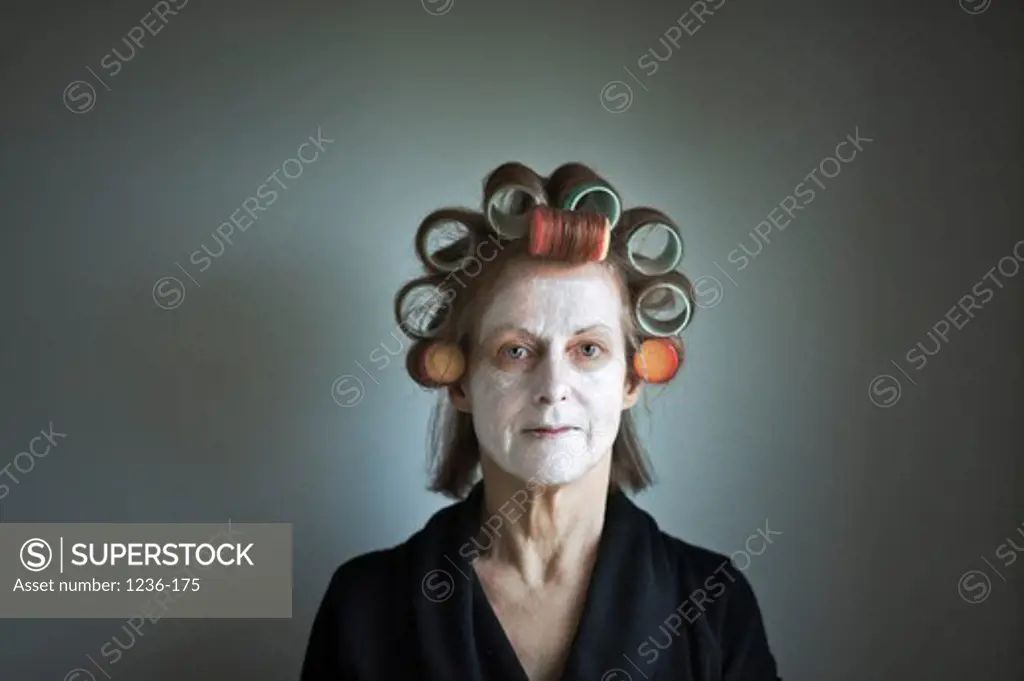Studio portrait of woman wearing large hair curlers and face mask