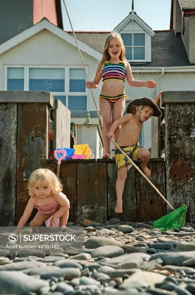 United Kingdom, Wales, Three children with fishing nets in front of beach house