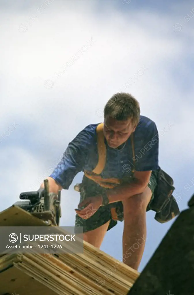 Low angle view of a carpenter cutting wood using an electric saw