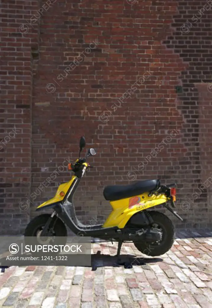 Motor scooter parked in front of a brick wall