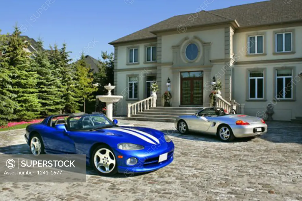 Two cars parked in front of a house