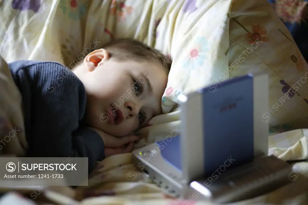 Boy lying in bed looking at a video game