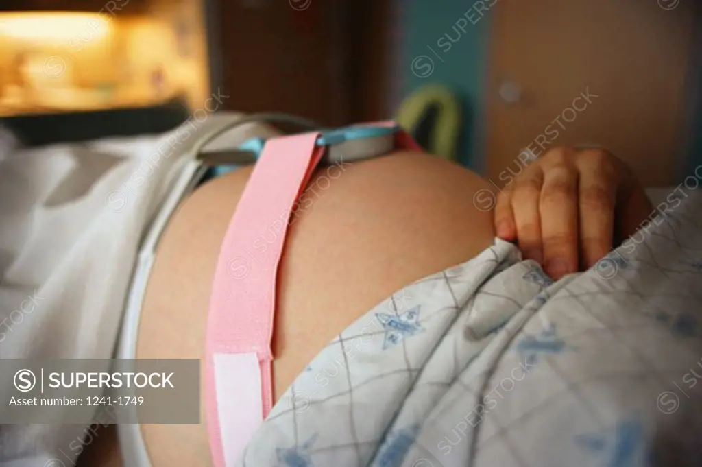 Close-up of a monitoring device strapped to a pregnant woman's abdomen