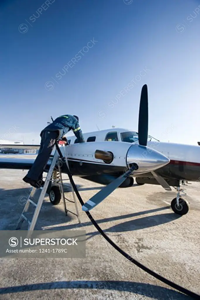 Rear view of a man refueling an airplane