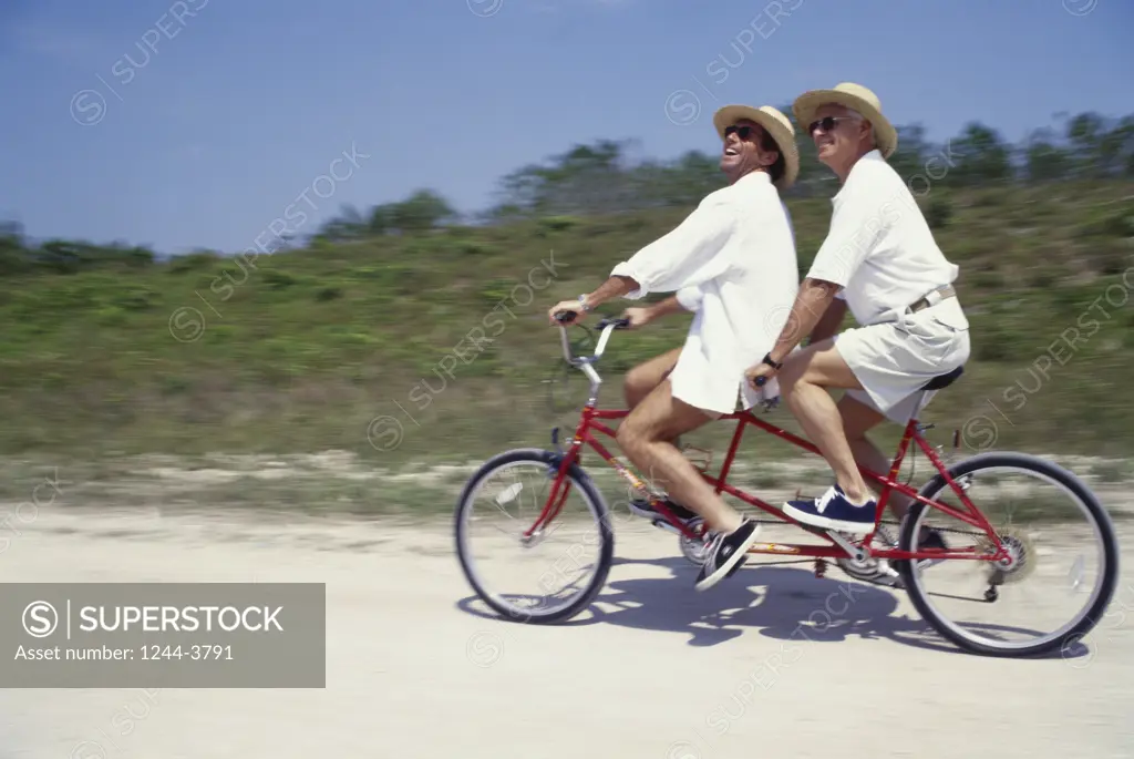 Young man and his father riding a tandem bicycle