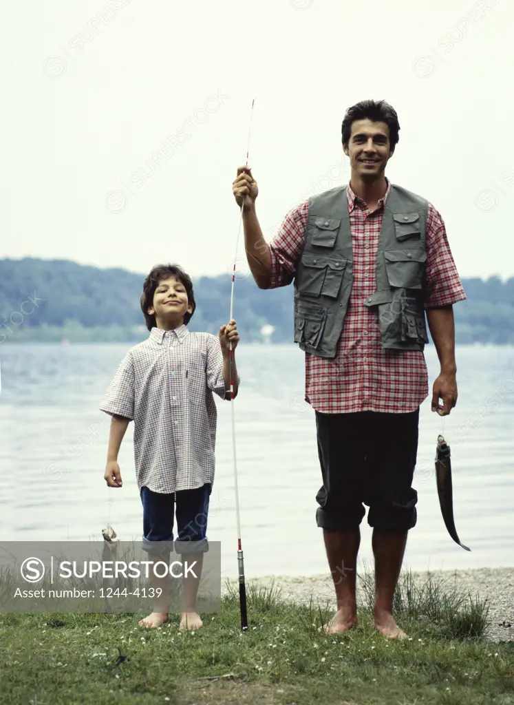 Father and son holding a fish and a fishing rod