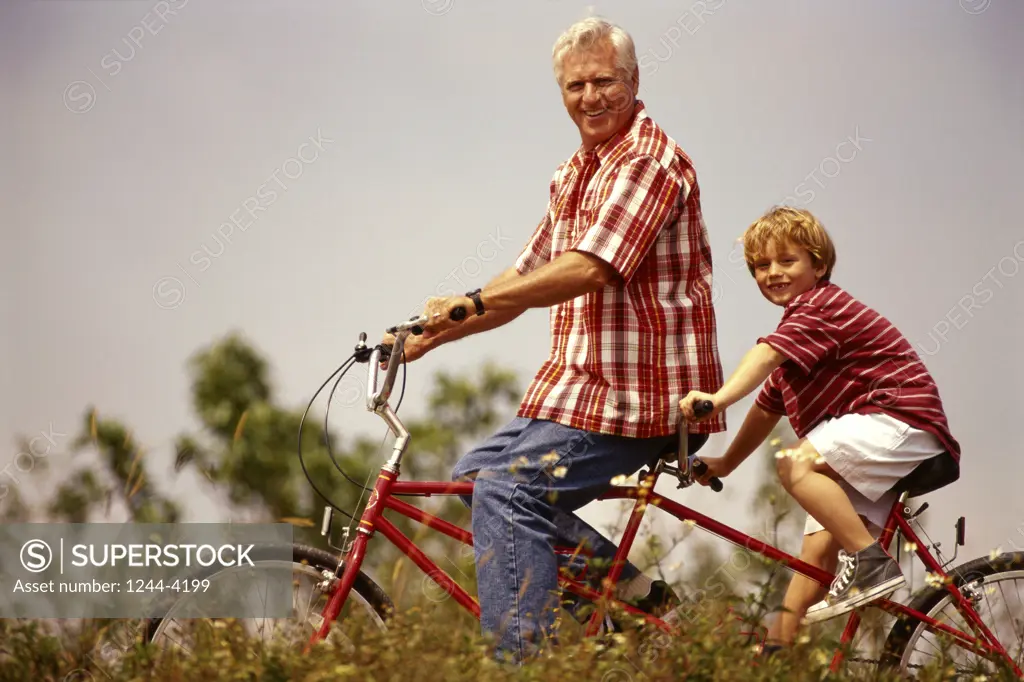 Grandfather riding a tandem bicycle with his grandson
