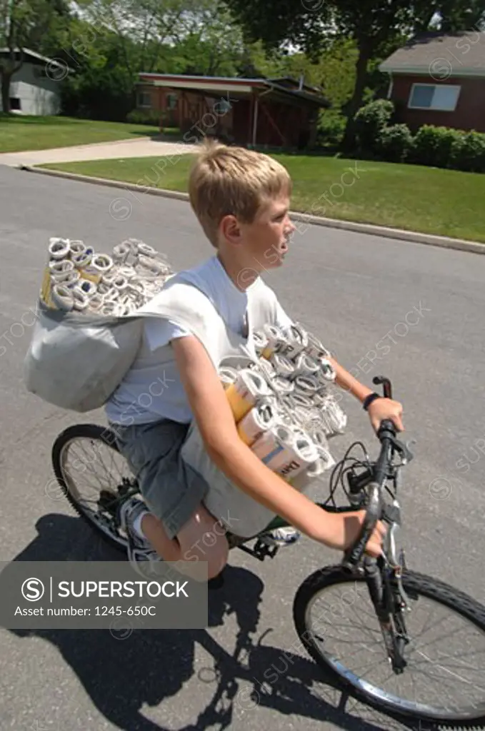 Paper delivery boy carrying newspapers on a bicycle