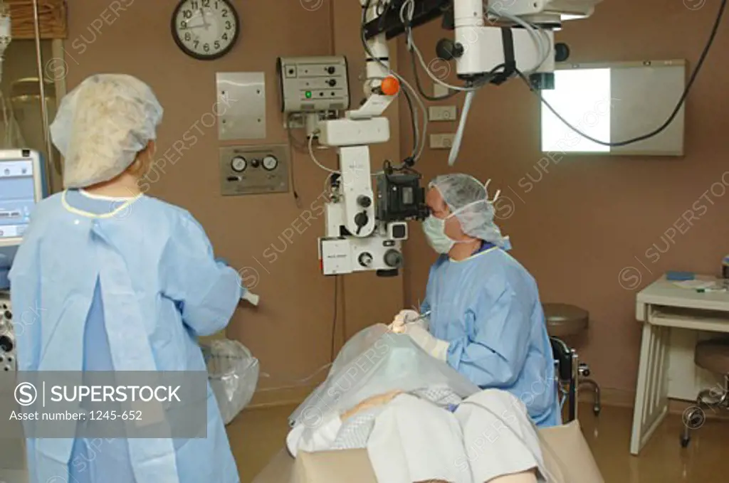 Female surgeon operating on a patient's eye with another female surgeon standing near her