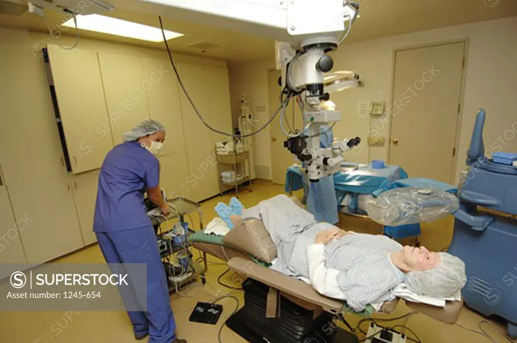 Rear view of a female surgeon preparing a patient for laser surgery