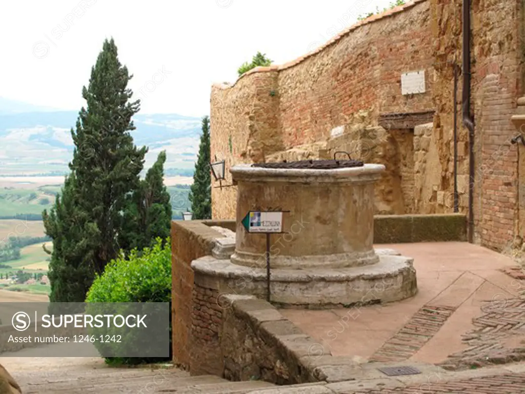 Italy, Tuscany, Province of Siena:  Pienza, old well, part of old town wall