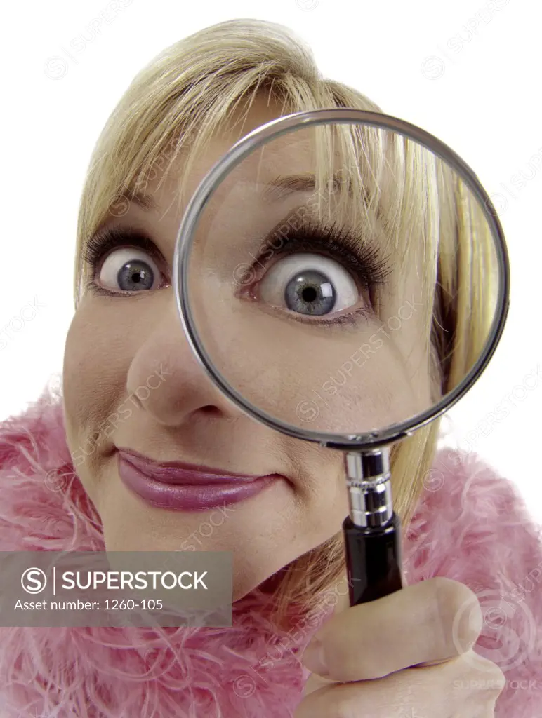 Close-up of an eccentric woman looking through a magnifying glass