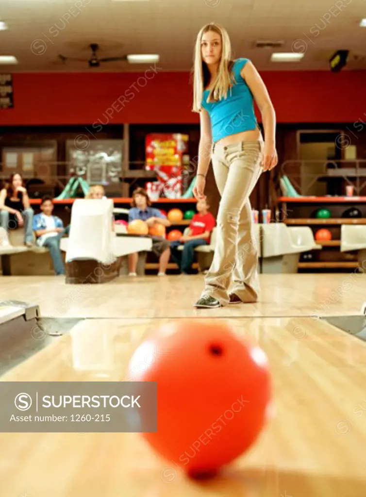 Low angle view of a teenage girl watching a bowling ball