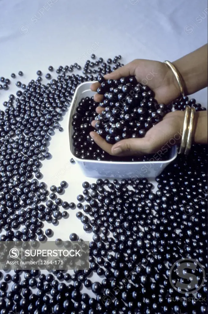 High angle view of a woman's hand holding black pearls