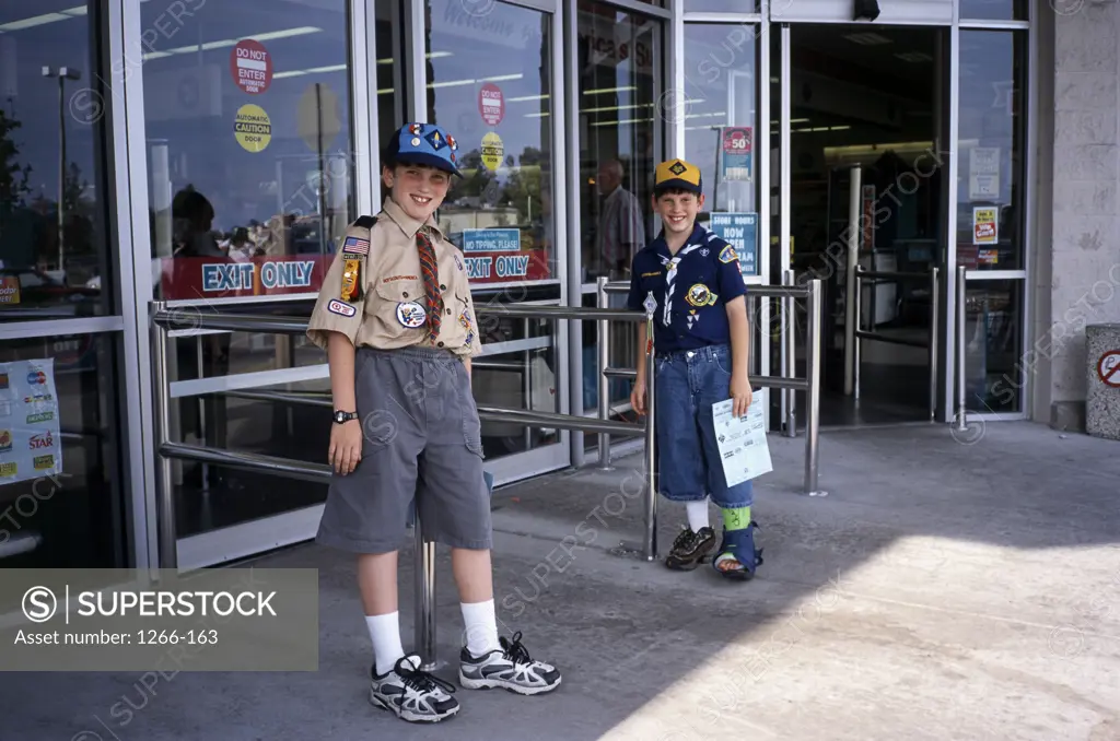 Portrait of two boys standing outside a store
