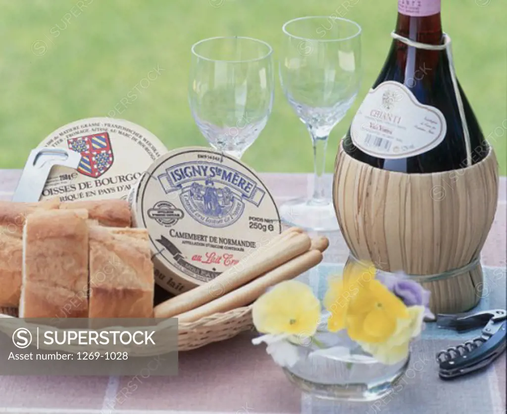 Close-up of a bread basket with wine glasses and a wine bottle on a table
