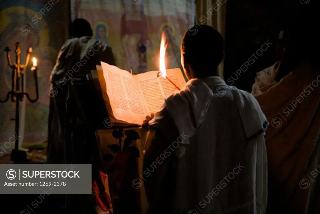 Rear view of a monk reading the Bible in a church, Medhane Alem Church, Lalibela, Ethiopia