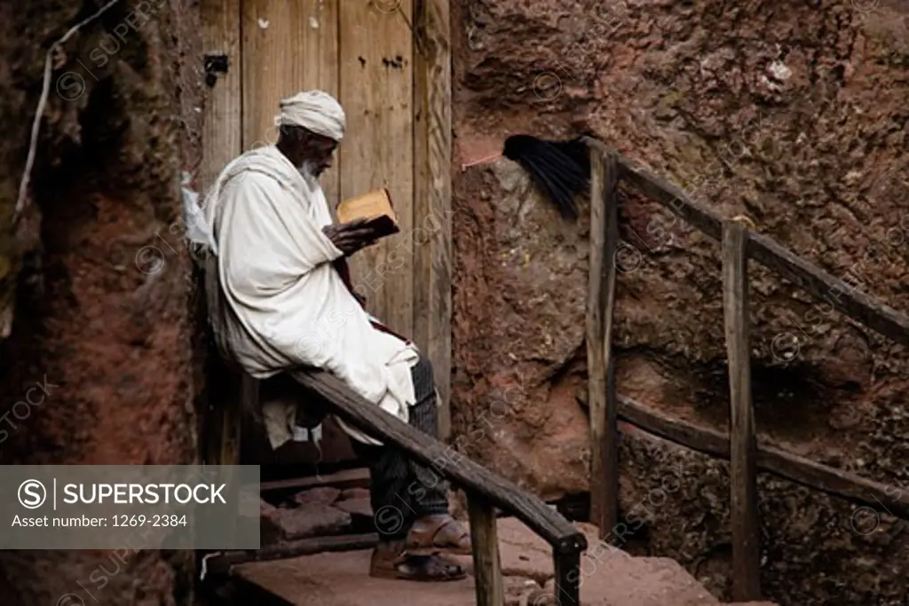 Monk reading the Bible in front of a church, Golgotha Church, Lalibela, Ethiopia