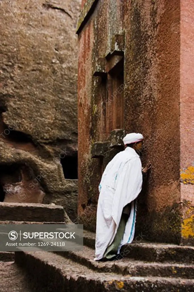 Priest praying in front of the wall of a church, St. George Church, Lalibela, Ethiopia