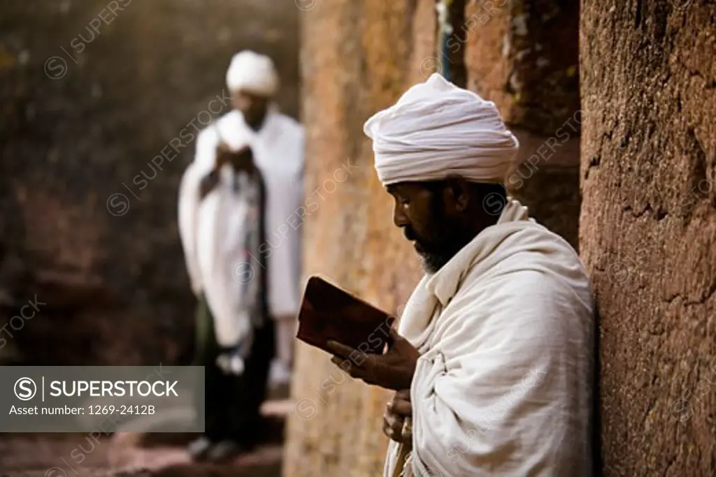 Two priests reading Bibles in front of a church, St. Maryam Church, Lalibela, Ethiopia