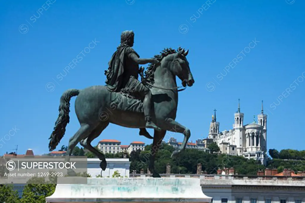 Statue of Louis XIV at a town square with a cathedral in the background, Place Bellecour, Basilica Notre Dame de Fourviere, Lyon, Rhone-Alpes, France