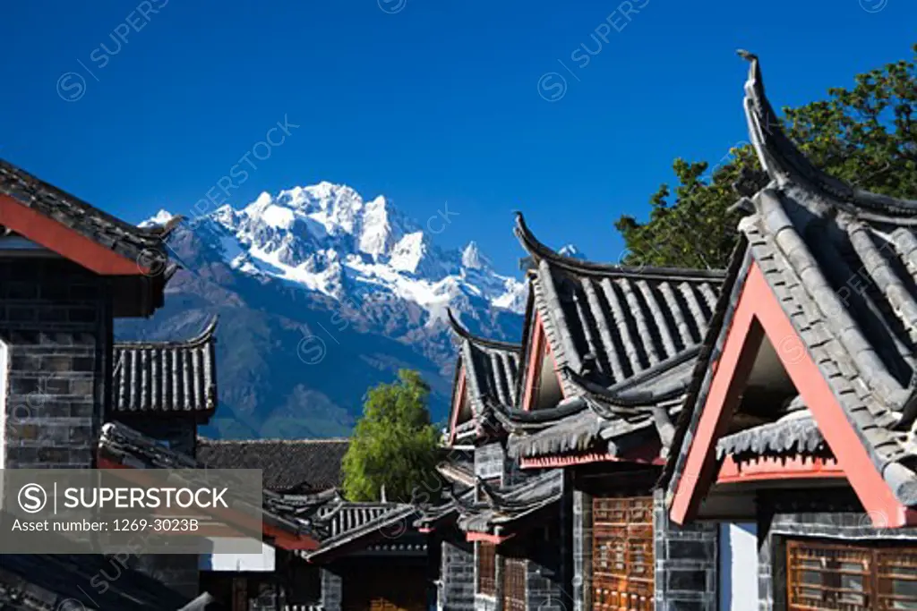 Buildings in a town with a mountain in the background, Jade Dragon Snow Mountain, Lijiang, Yunnan Province, China