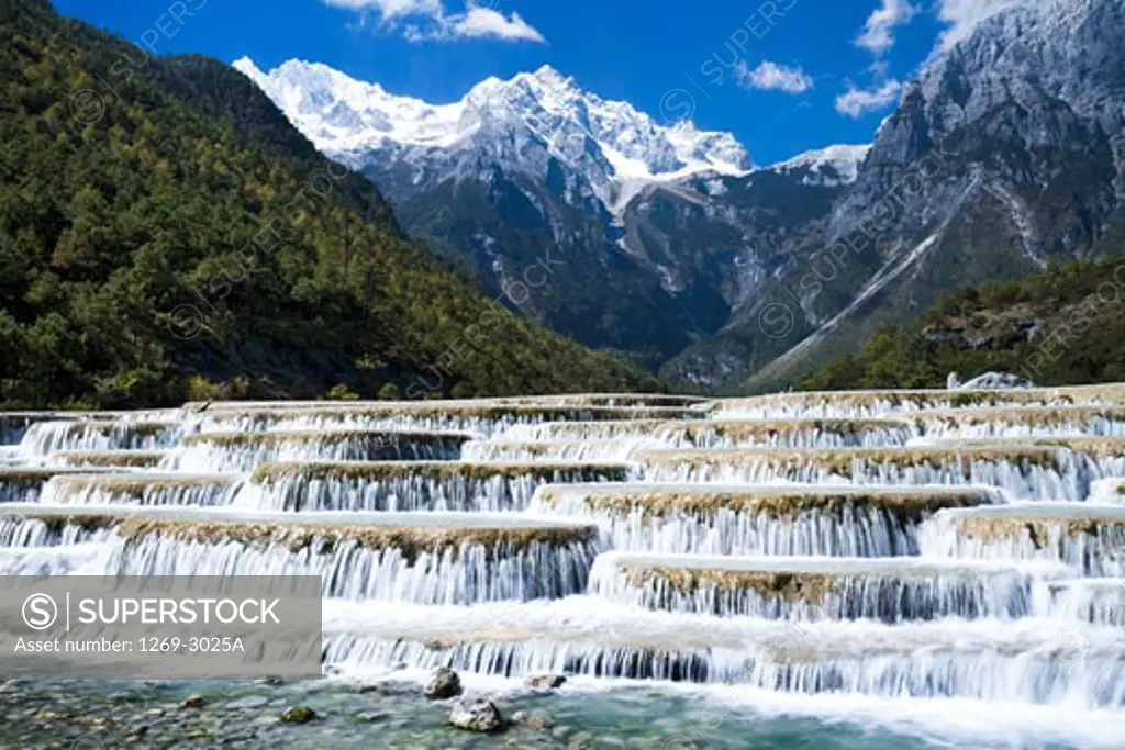 Cascading waterfall in front of a mountain range, Baishuitai Falls, Jade Dragon Snow Mountain, Lijiang, Yunnan Province, China