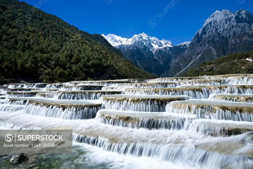 Cascading waterfall in front of a mountain range, Baishuitai Falls, Jade Dragon Snow Mountain, Lijiang, Yunnan Province, China