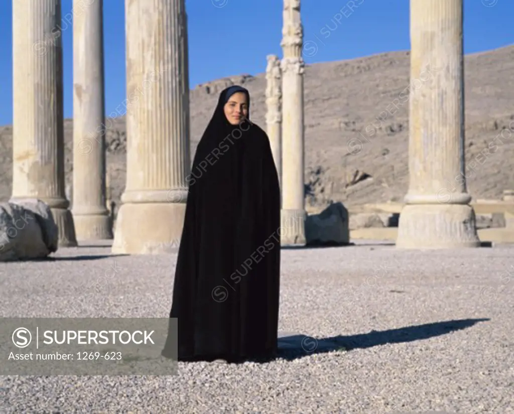 Portrait of a young woman wearing a religious veil standing in front of columns, Persepolis, Iran
