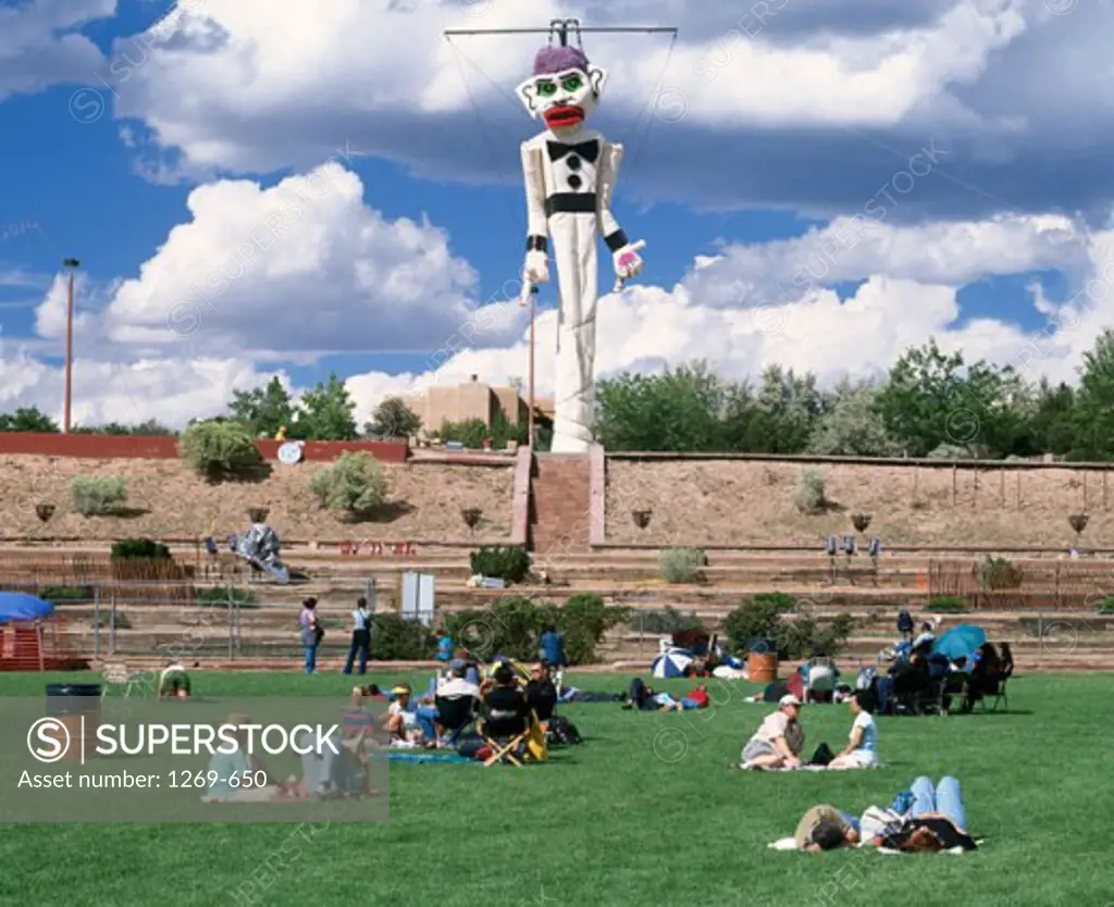 Tourists sitting in a park in front of an effigy, Zozobra, Santa Fe, New Mexico, USA