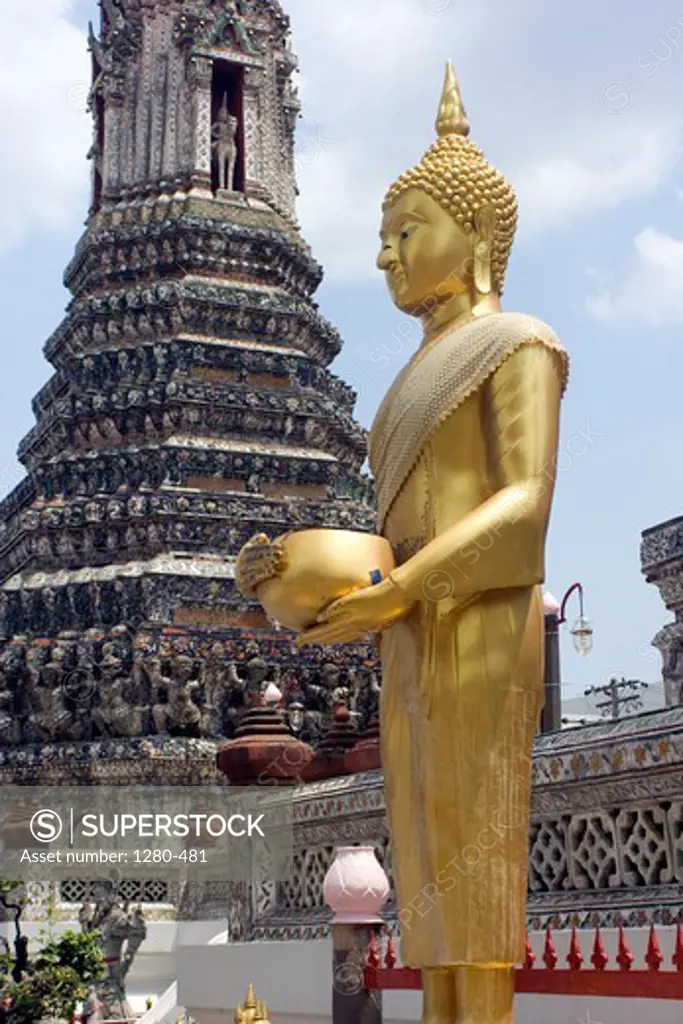 Thailand, Bangkok, part of golden statue with temple in background