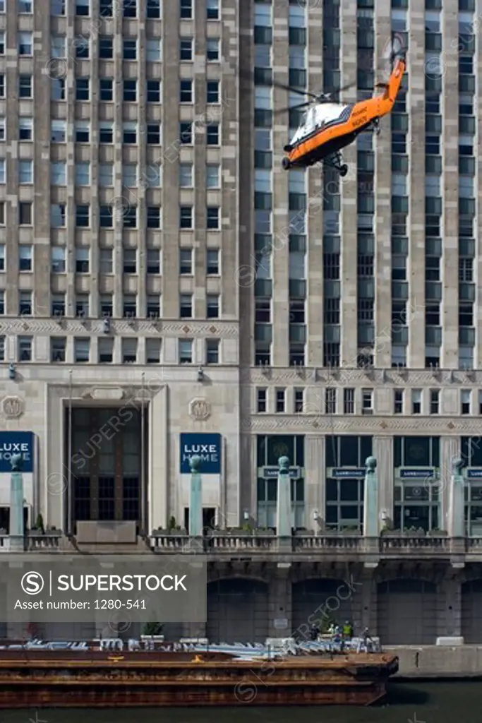 Helicopter lifts steel beams from a barge on the Chicago River in front of Merchandise Mart, Chicago, Cook County, Illinois, USA