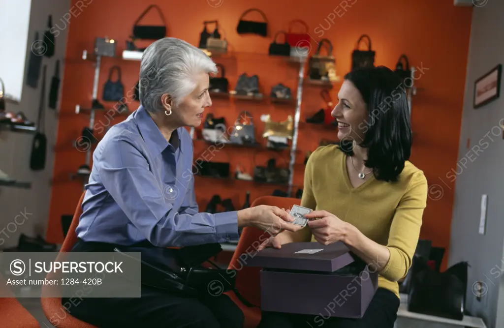 Senior woman giving credit card to shop assistant in shop,