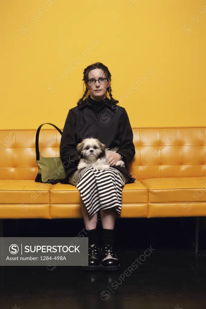 Young woman sitting on a couch holding a puppy in her lap