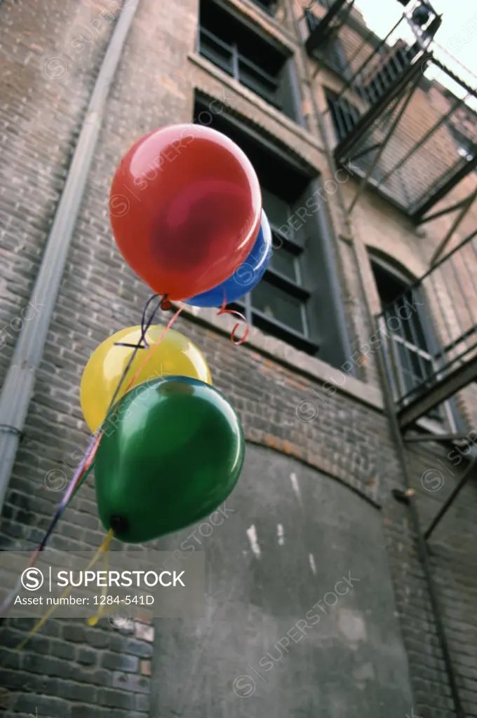 Colorful helium balloons in front of building,