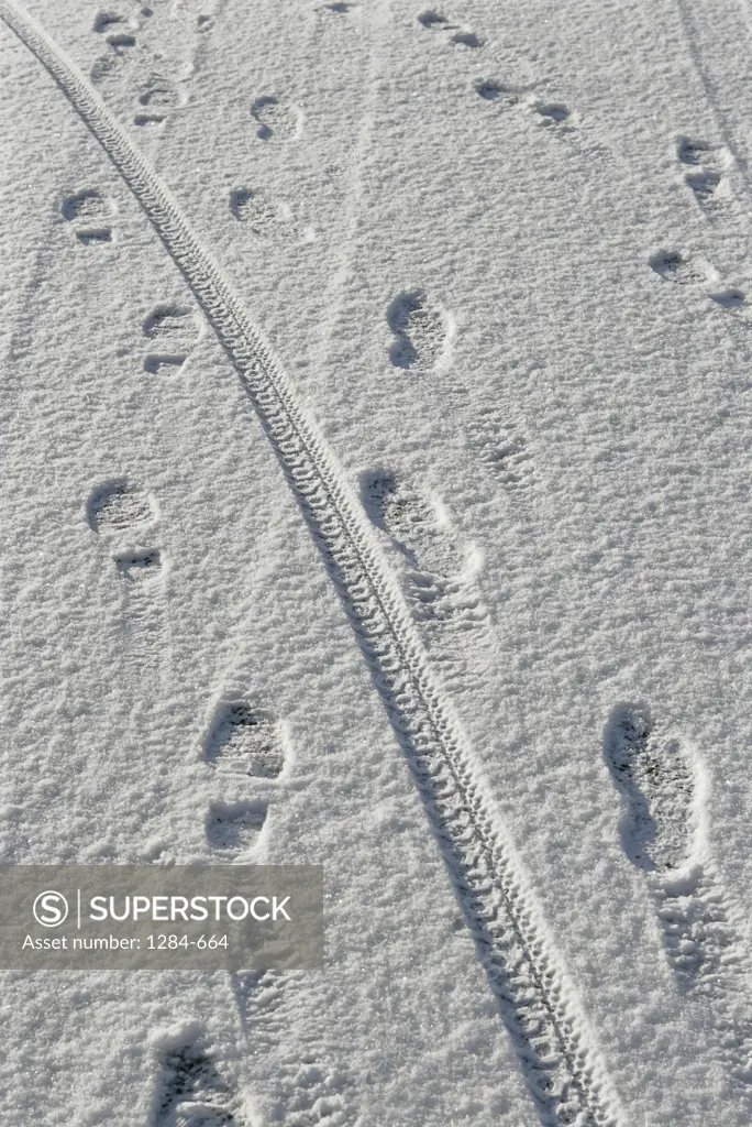 High angle view of footprints and tire tracks in snow