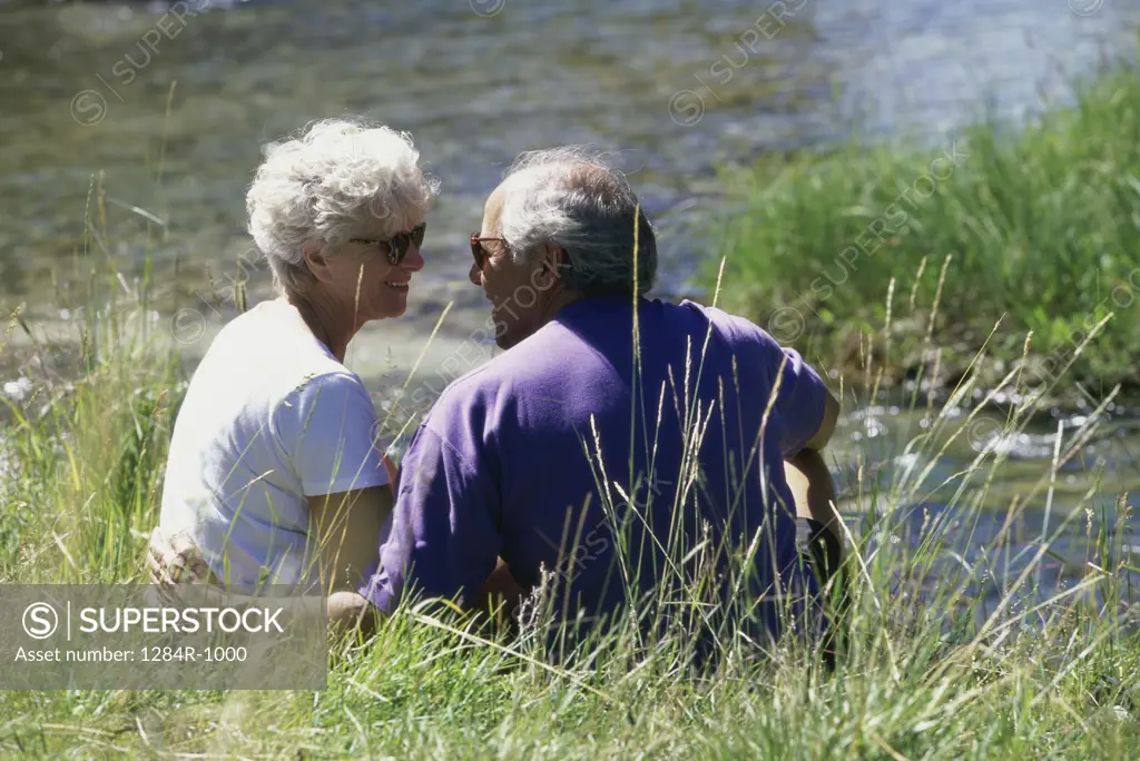 Senior couple sitting together on the bank of a river