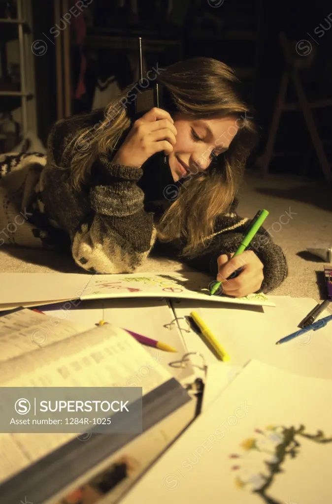 Teenage girl lying on the ground talking on a telephone