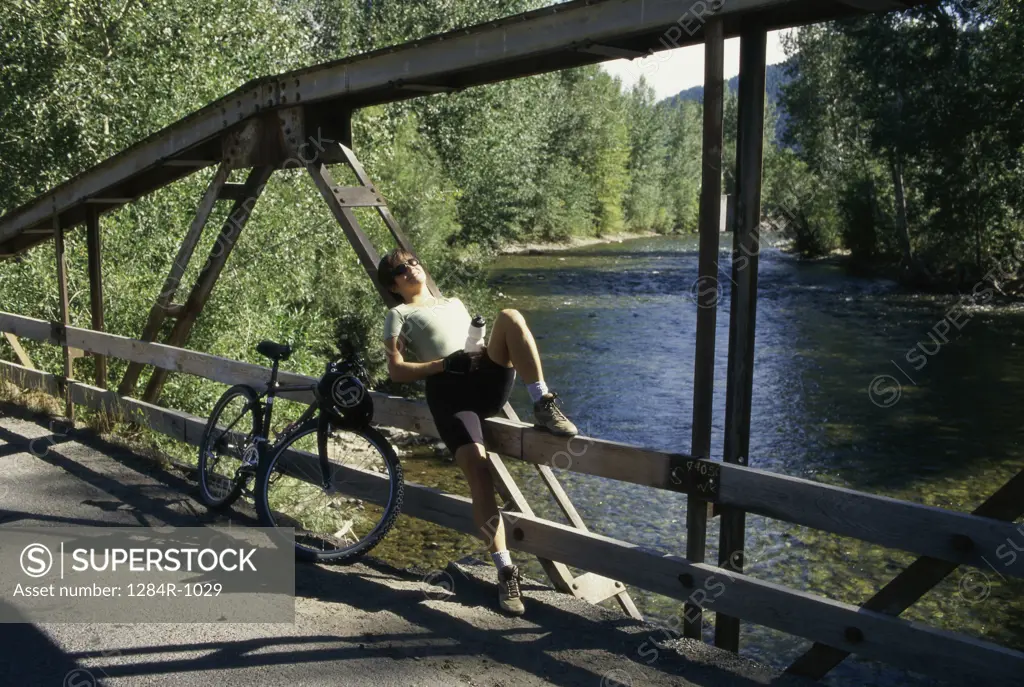 Young woman sitting on a bridge, Sun Valley, Idaho, USA
