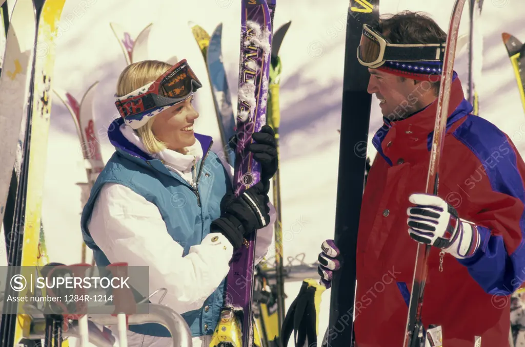 Young couple holding skis and ski poles