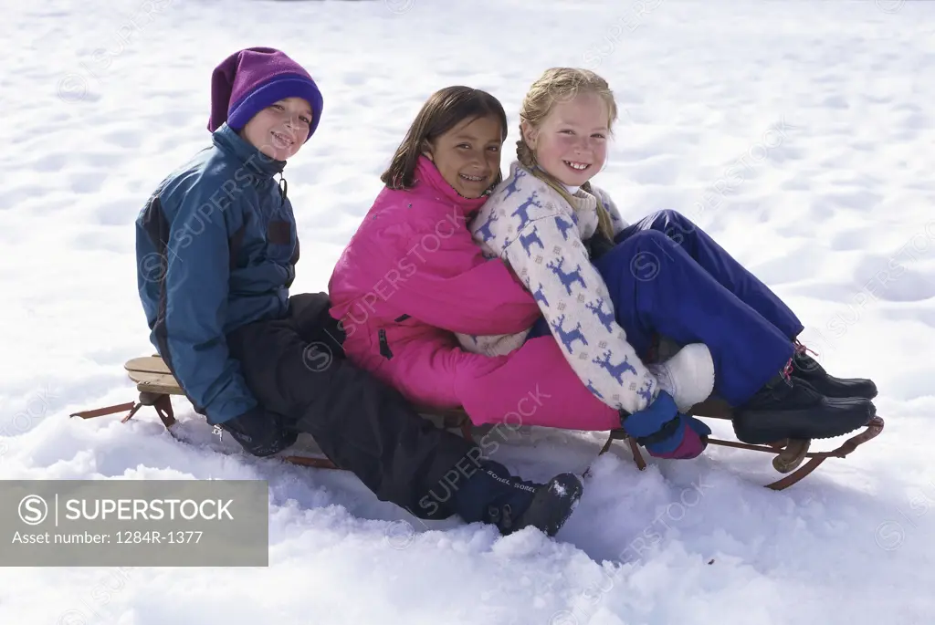 Portrait of a boy and two girls sitting on a sled