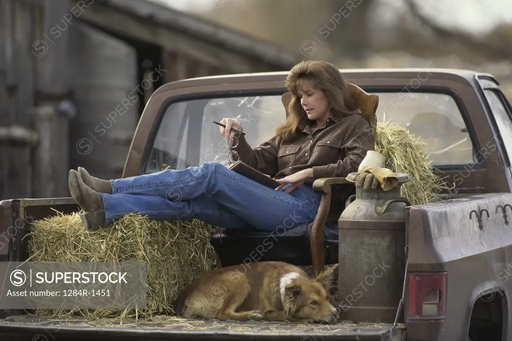 Woman sitting on a chair in a pick-up truck with her dog