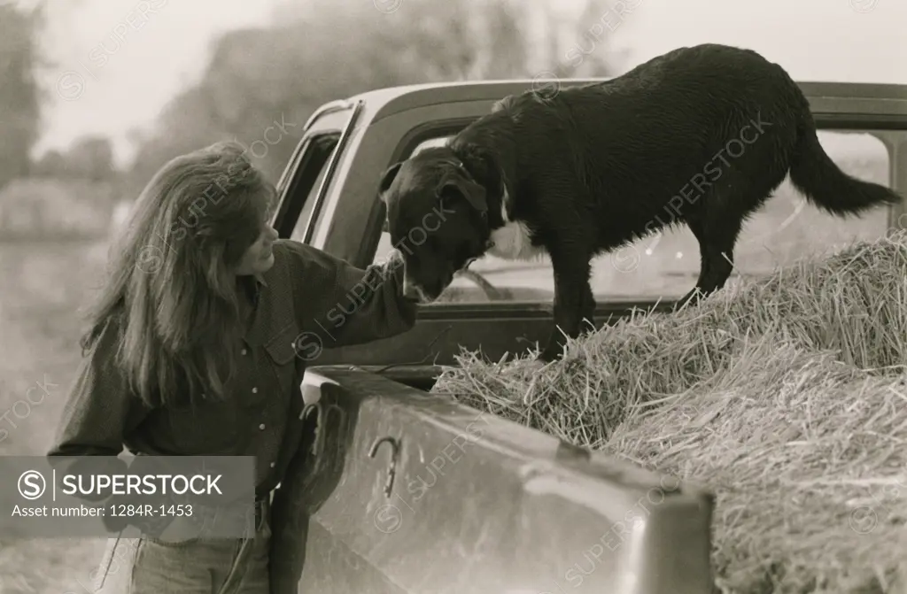 Woman standing with her dog at a pick-up truck