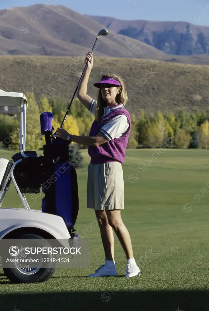 Young woman taking a golf club from a golf bag