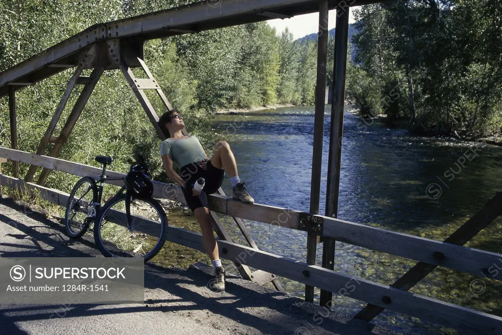 Young woman leaning against a railing on a bridge, Sun Valley, Idaho, USA