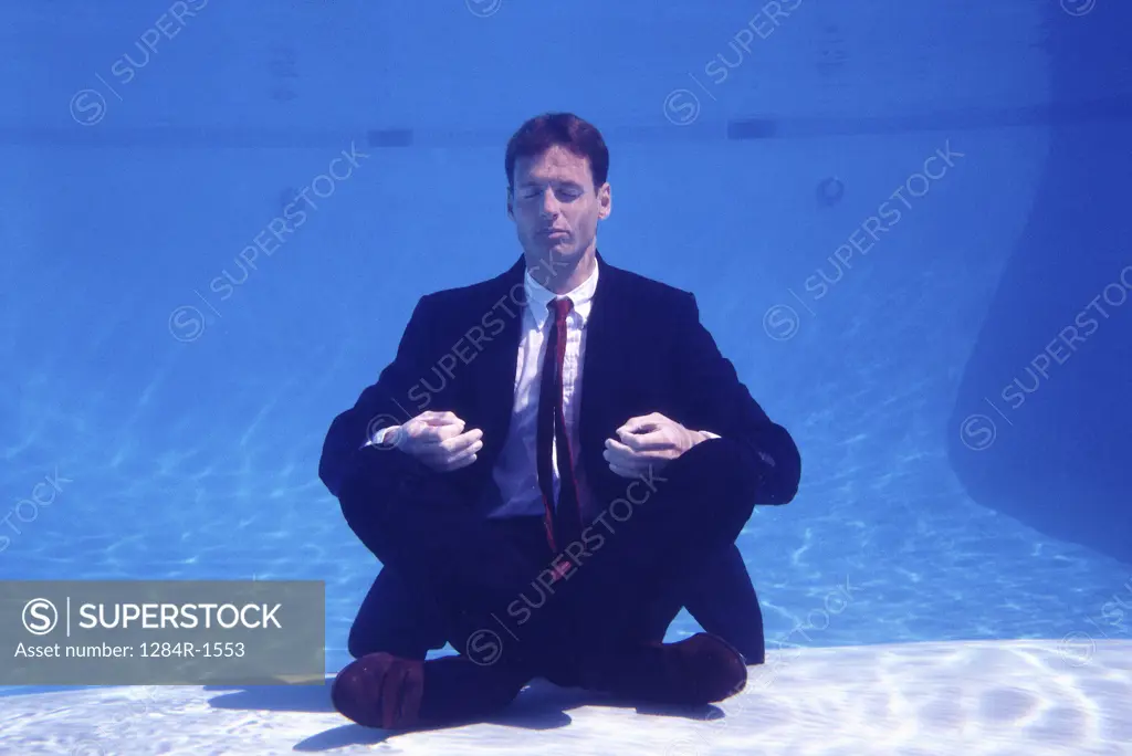 Businessman sitting underwater meditating