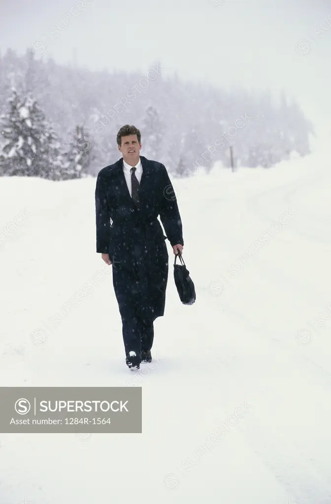 Businessman walking on a snow covered road