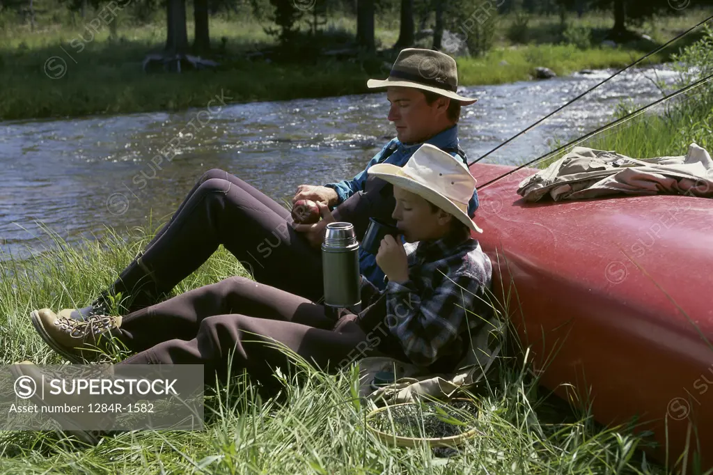 Father and son sitting by a river