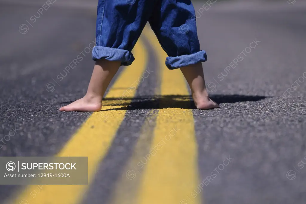 Low section view of a person's feet standing on a road