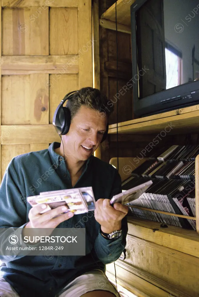 Mid adult man wearing headphones and holding CD's